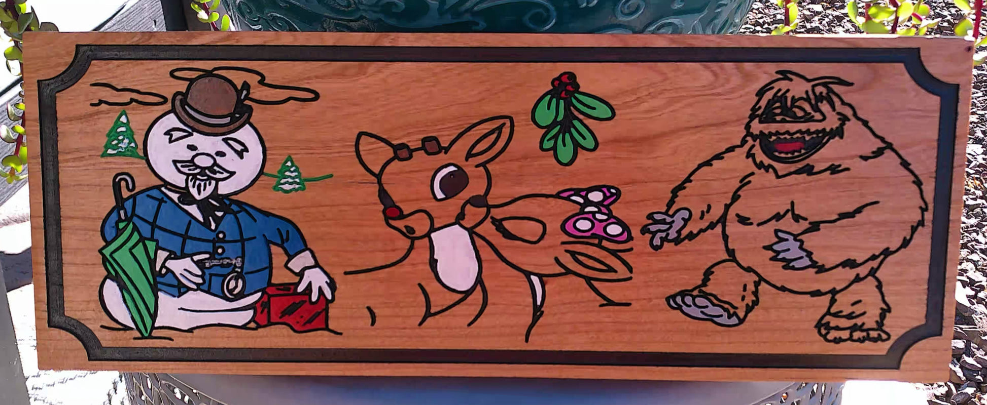 Wooden plaque with engraved illustration of a snowman, reindeer, and bear.