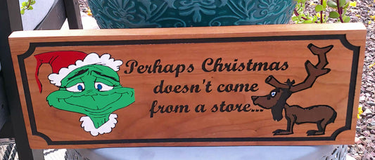 Wooden sign with Grinch and reindeer illustration and text 'Perhaps Christmas doesn't come from a store'.