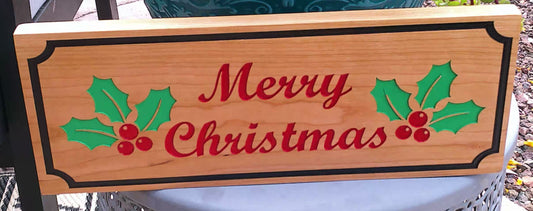 Wooden Christmas sign with holly leaves and berries on a blurred outdoor background