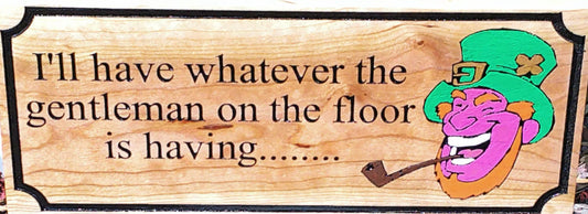 Wooden sign with cartoon character and text 'I'll have whatever the gentleman on the floor is having', framed by a decorative border.
