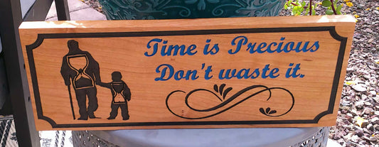 Wooden sign with engraved text and silhouette of a man and child, set outdoors.