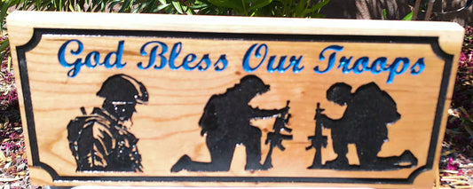 Wooden sign with silhouettes of soldiers and 'God Bless Our Troops' text.
