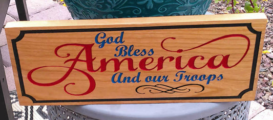 Wooden sign with 'God Bless America And our Troops' text on a wooden stand.