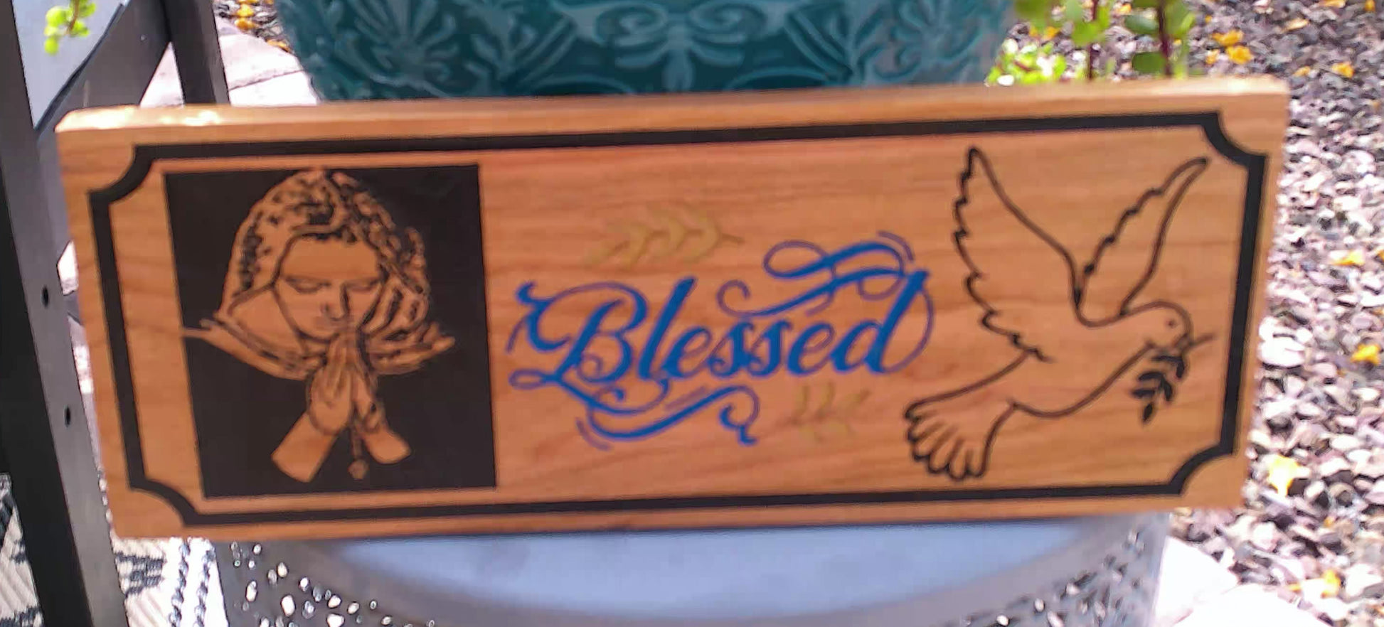 Wooden sign with engraved design of a woman, dove, and 'Blessed' text on a natural wood background.