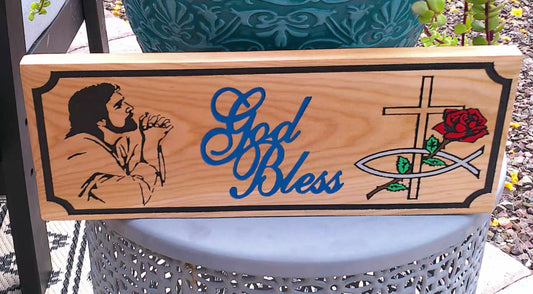 Wooden sign with engraved designs and 'God Bless' text on a decorative stand.