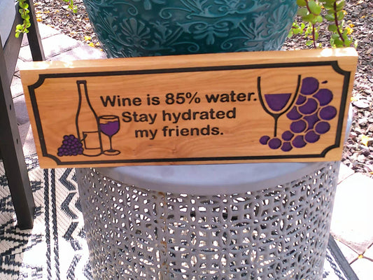 Wooden sign with humorous wine quote on a decorative stand outdoors.