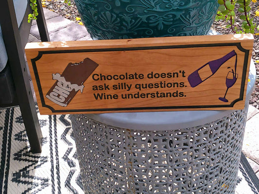 Wooden sign with humorous quote about chocolate and wine on a decorative chair.